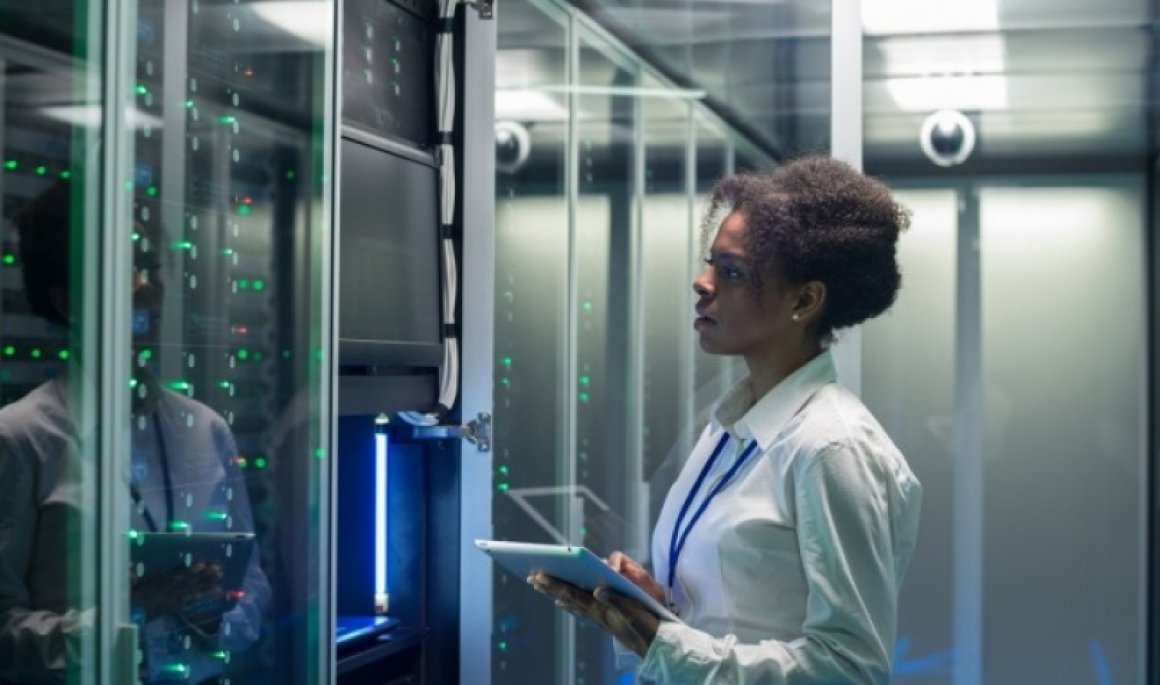 cybersecurity professional works on a tablet in a data center