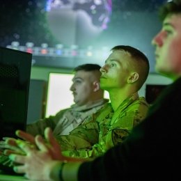 Three students in front of a computer in the Norwich University Cyber War Room.