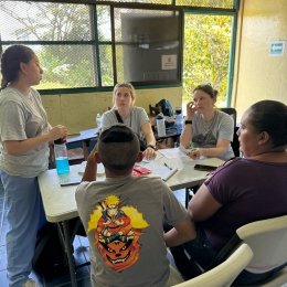 A group of Norwich University School of Nursing students sitting around a table in a screened room with trees outside