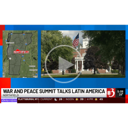 A screen shot of a video news segment from WCAX titled "WAR AND PEACE SUMMIT TALKS LATIN AMERICA". On the screen are an map of Vermont showing where Northfield is and an image of a United States Flag waving in front of Jackman Hall on the Norwich University campus. 