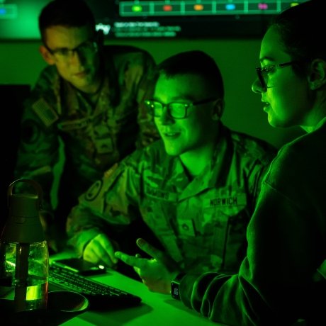 Three students in front of a computer in the Norwich University Cyber War Room.