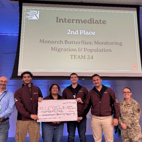 Norwich team at Rowdy Datathon holding their 2nd place prize in front of a sign that says "Intermediate 2nd Place - Monarch Butterflies: Monitoring Migration & Population (Team 24)"