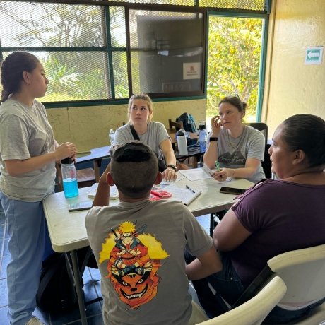 A group of Norwich University School of Nursing students sitting around a table in a screened room with trees outside