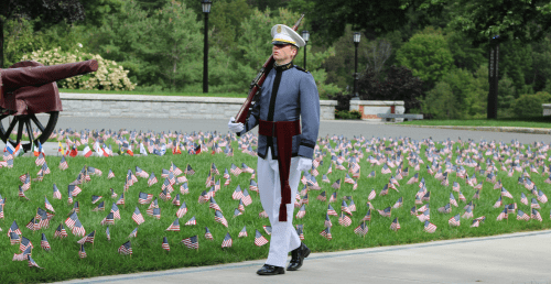 Norwich cadet marching on the UP next to flags.