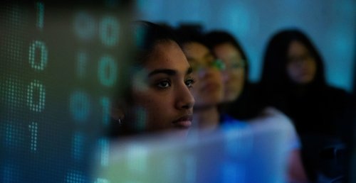 Students sitting in cyber class behind computers.