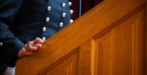 Speaker at lectern, showing class ring, inaugural Bonds of Gold Ring Melt