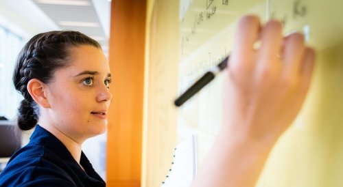 Norwich Mathematics Student Writing Complex Formulas on Whiteboard