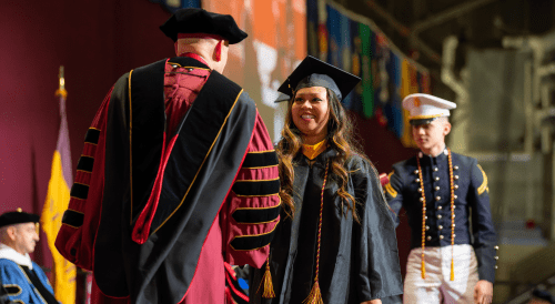 Norwich student at commencement shaking hands.