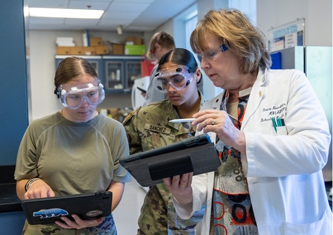 Faculty member helping two students on her iPad in a lab.