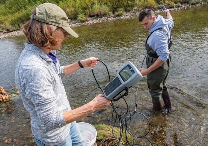 Student working in the Dog River with faculty for biology class.