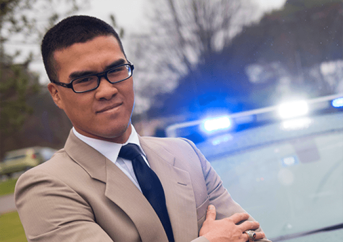 Criminal Justice major posing in front of a cop car.