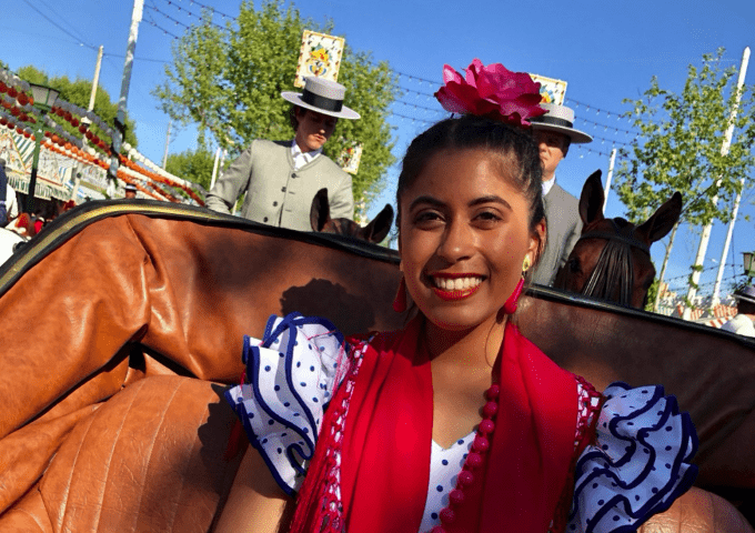 Student riding in a horse carriage dressed in traditional Spanish garb.