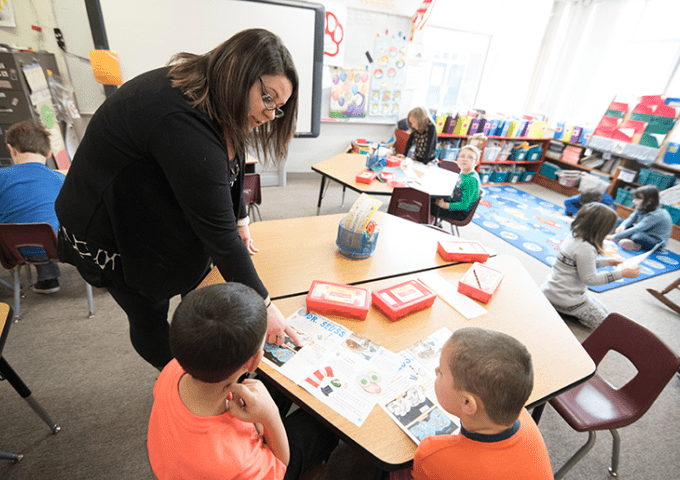 Teacher working with children in an elementary classroom setting.