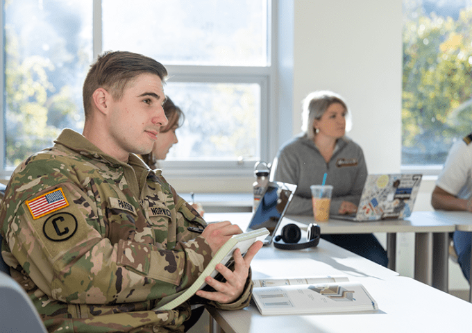 Corps of cadets student taking notes in class.