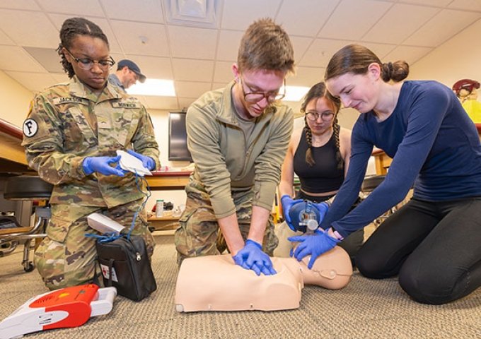 Group of students learning CPR on a CPR doll.