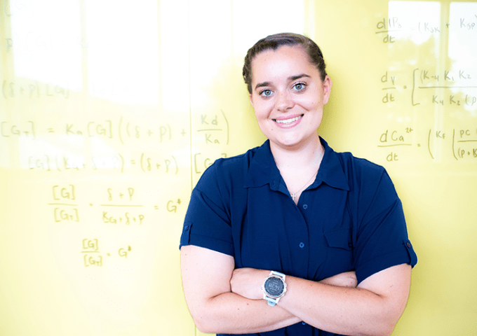 Student standing in front of board with math equations covering it.