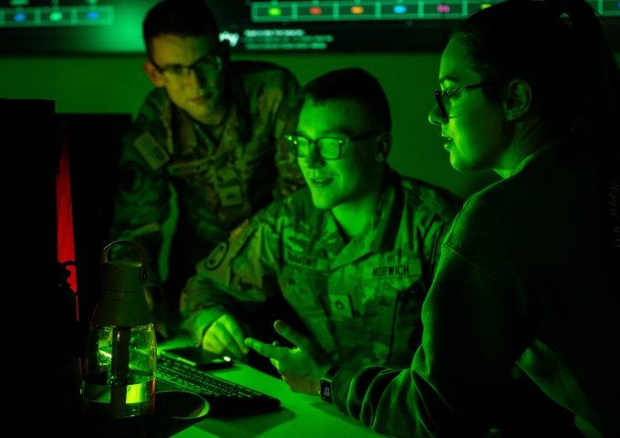 Three students in front of a computer in the Norwich University Cyber War Room.