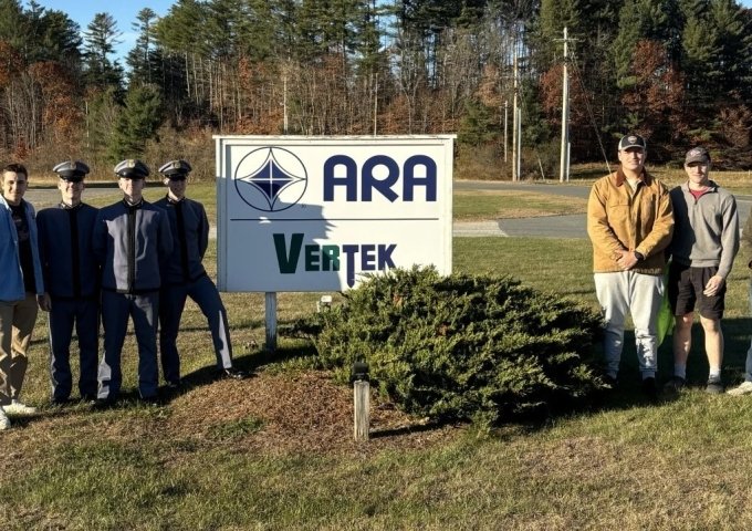 Norwich University students standing in front of the sign for Applied Research Associates in Randolph, VT