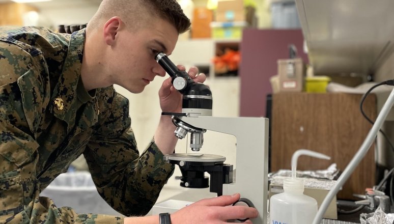 Corps male student using a microscope.