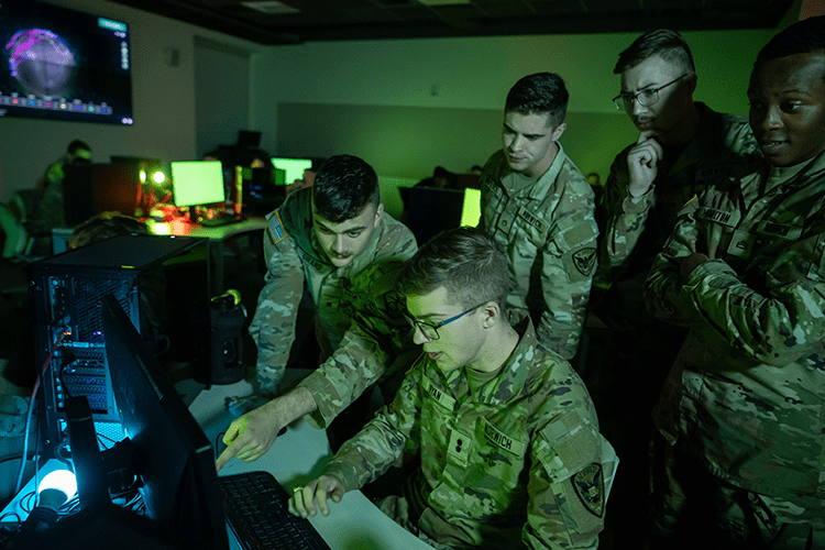 Group of Corps cyber security students working on a computer in the war room.