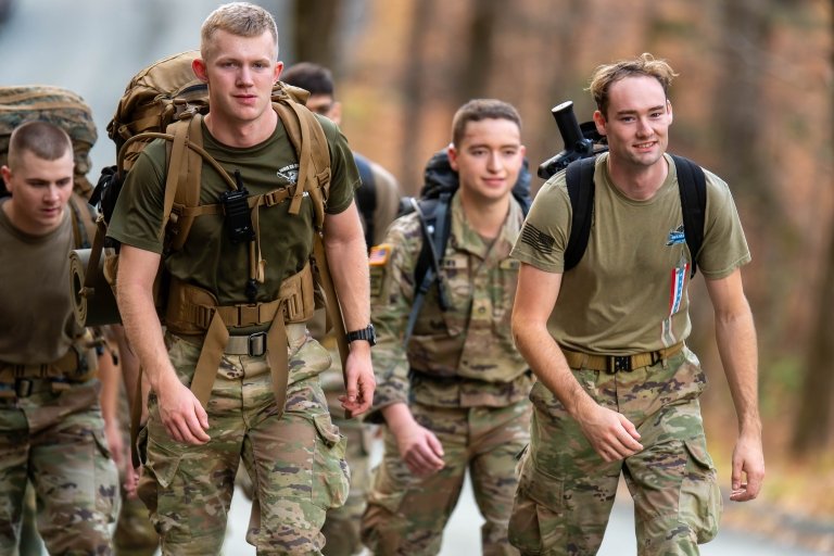 Cadets participating in the Norwich University Legacy March, marching on a road surrounded by trees and fallen leaves