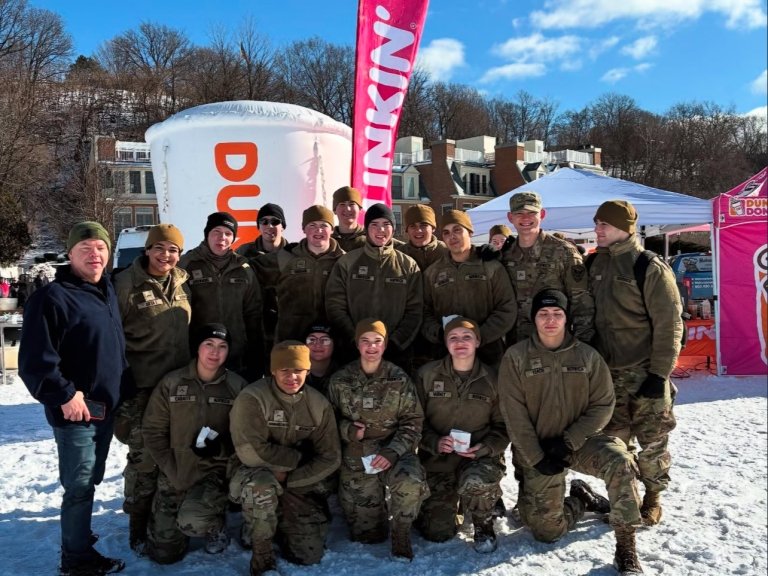 A group of Norwich University Corps of Cadets students in front of a Dunkin Donuts flag at the 30th annual Penguin Plunge